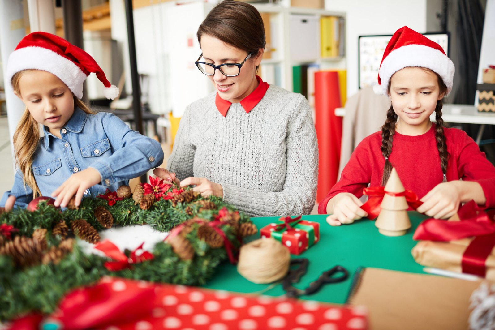 Mother and daughters decorating a Christmas wreath together